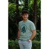 Hombre sonriendo con Camiseta Positano de Flow Mico en verde salvia con logo de meditación en el pecho