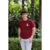 Hombre sonriendo con Camiseta Burgundy Savannah de Flow Mico en burdeos mostrando la etiqueta azul turquesa en manga