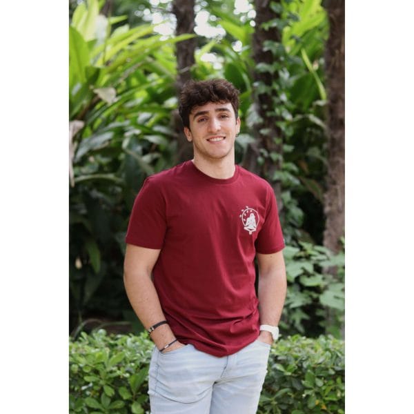 Hombre sonriendo con Camiseta Burgundy Savannah de Flow Mico en color burdeos en entorno natural