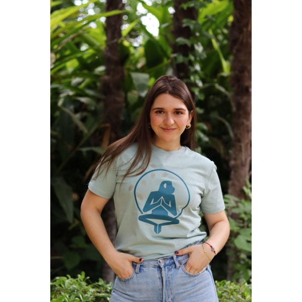 Mujer con Camiseta Positano de Flow Mico en verde salvia con logo de meditación en el pecho en entorno natural
