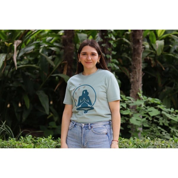 Mujer con Camiseta Positano de Flow Mico en verde salvia con logo de meditación visible en entorno natural