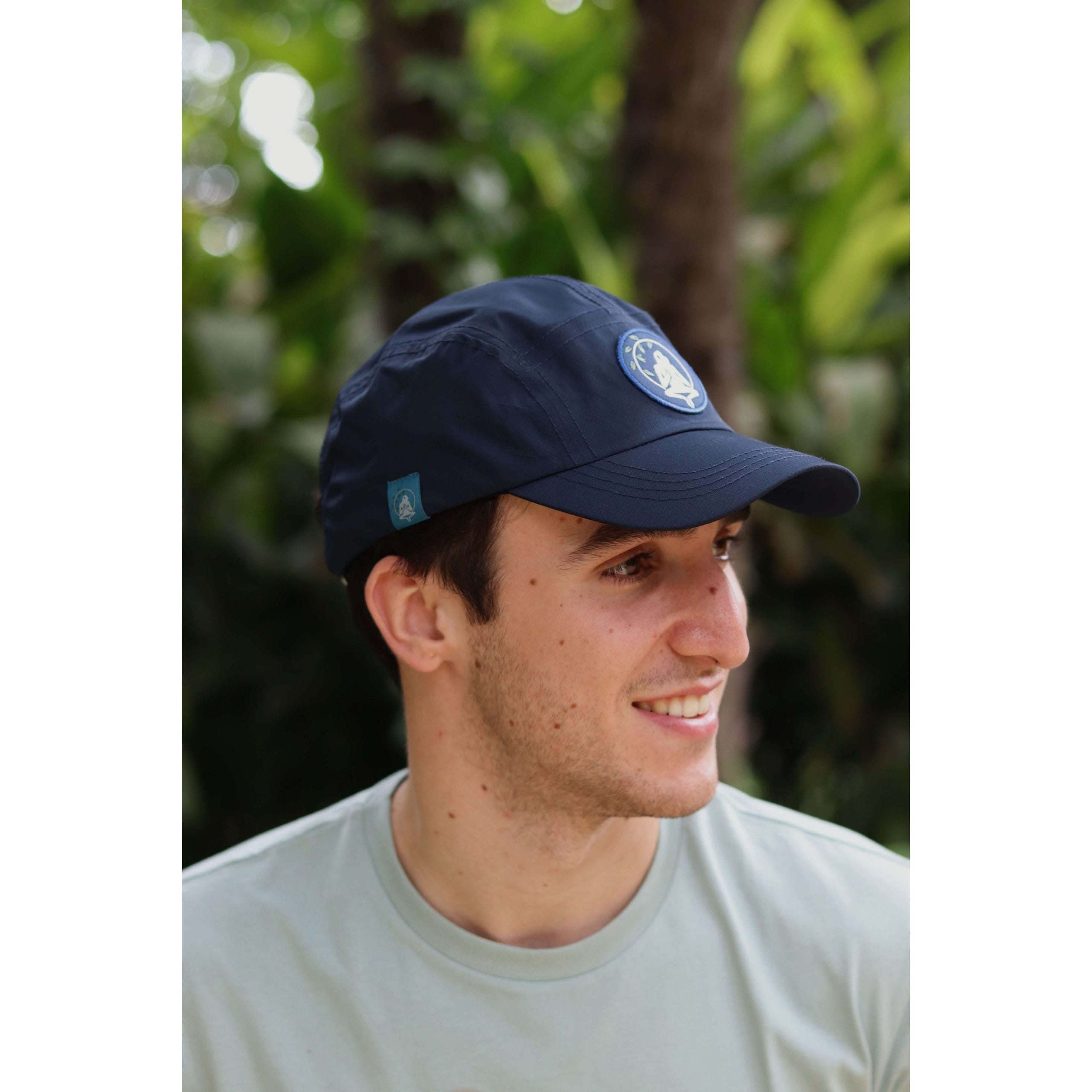 Gorra Yosemite Blue impermeable de material reciclado en azul navy, perfil lateral en modelo masculino, en entorno natural