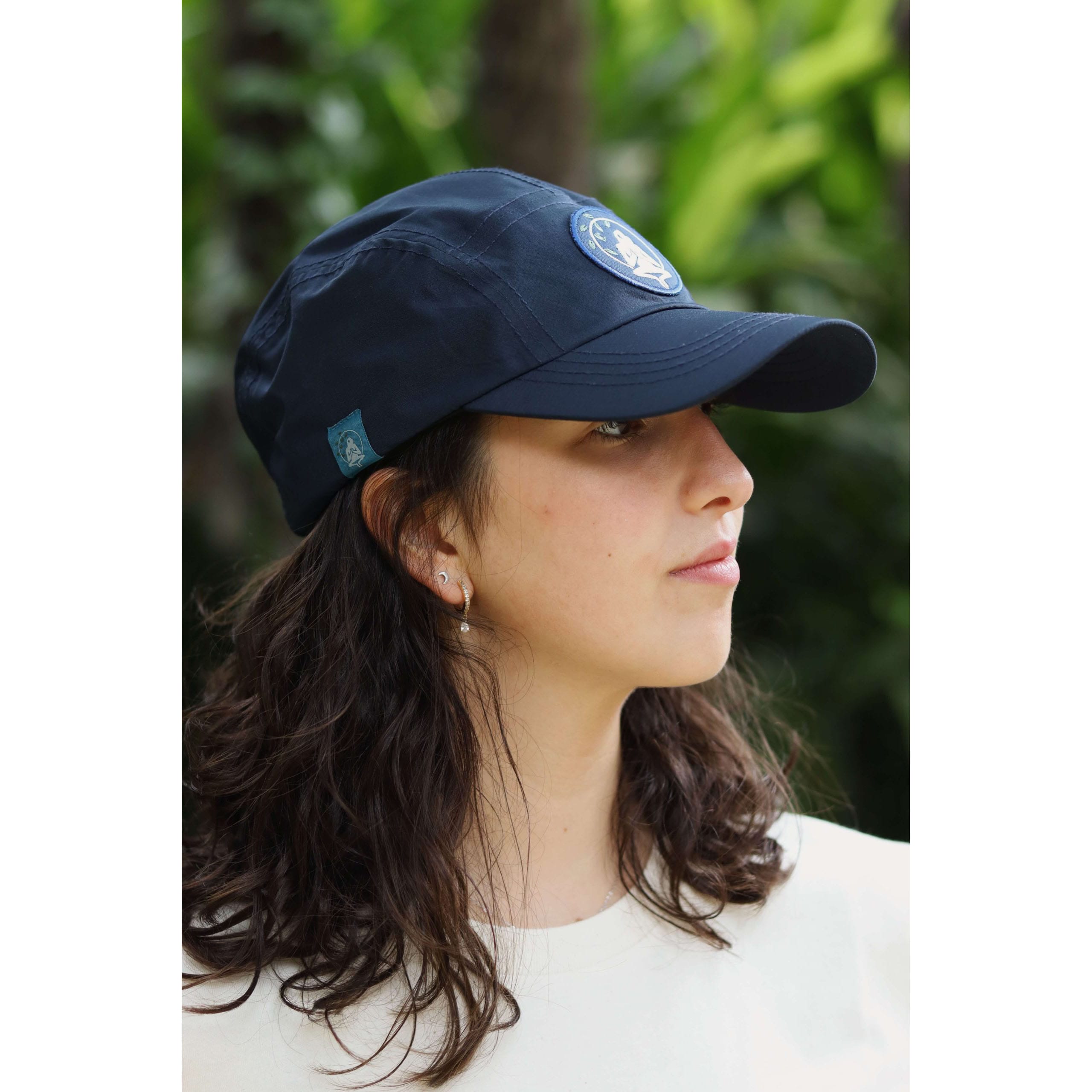 Gorra Yosemite Blue impermeable de material reciclado en azul navy, vista de perfil con etiqueta lateral, en entorno natural