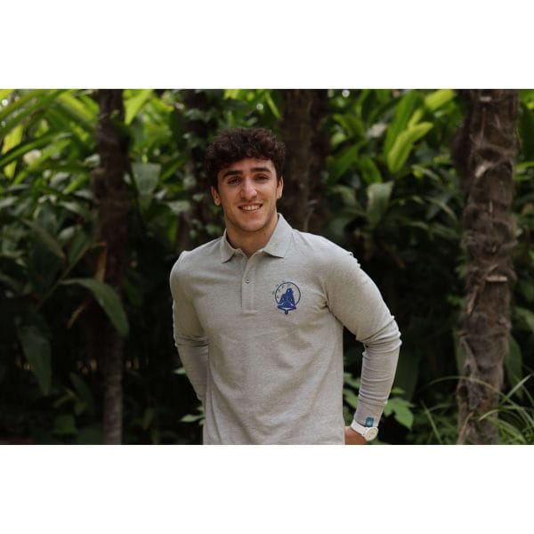 Hombre sonriendo con Polo Oslofiord de Flow Mico en gris jaspeado con manos en la espalda
