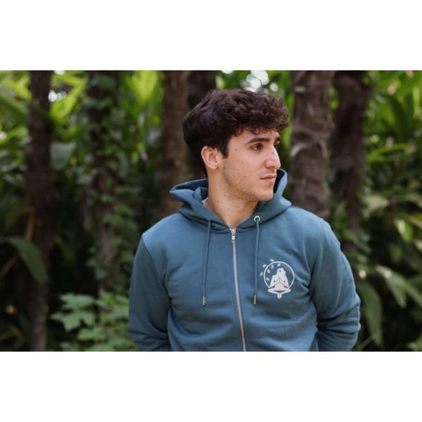 sudadera-balance-haven-hombre-lateral Hombre mirando a un lado con Sudadera Balance Haven de Flow Mico en azul petróleo con logo Flow Mico visible