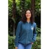 sudadera-balance-haven-mujer-frontal-2 Mujer sonriendo con Sudadera Balance Haven de Flow Mico en azul petróleo con cremallera y logo Flow Mico en el pecho