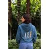 sudadera-balance-haven-mujer-trasera Vista trasera de mujer con Sudadera Balance Haven mostrando la ilustración de tres suricatos y texto Flow Mico